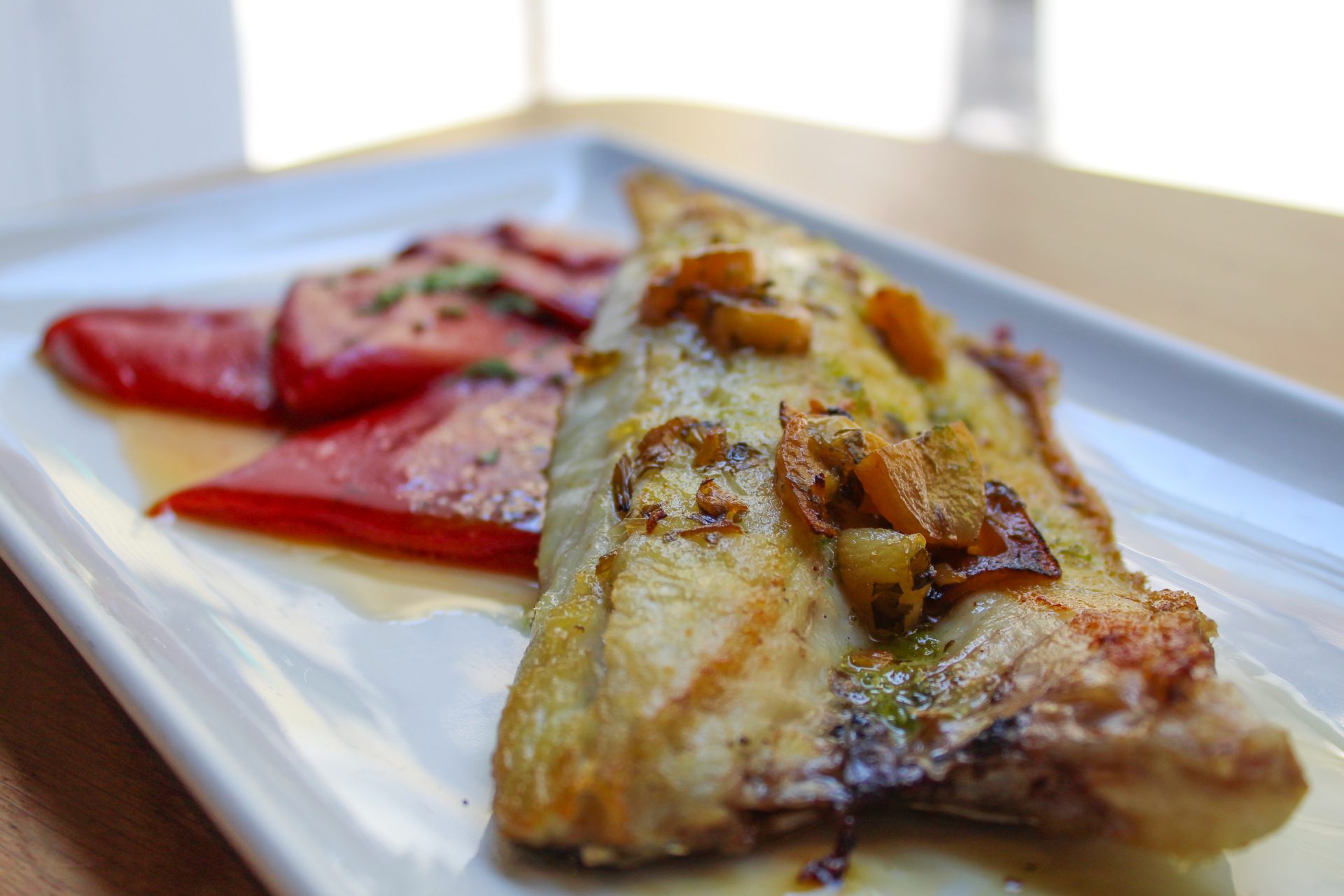 Lubina asada con refrito de ajo y piquillo