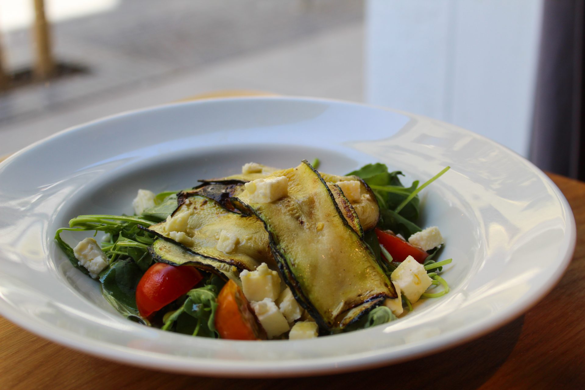 Ensalada de calabacín a la plancha, tomate cherry, queso feta, albahaca, pipas y rúcula