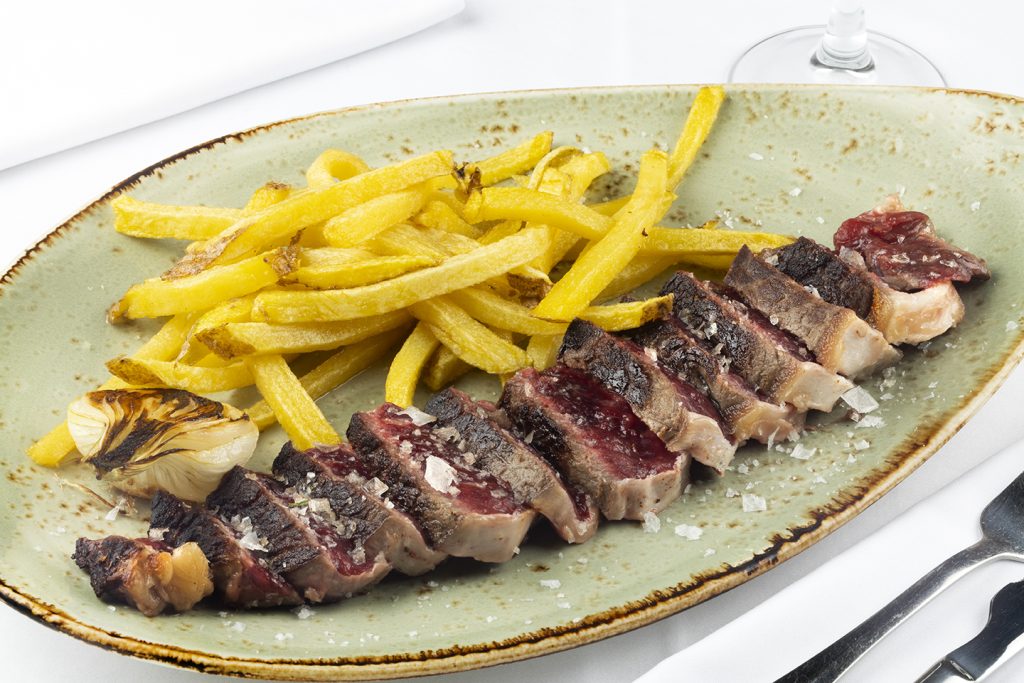 Lomo bajo de vaca nacional fileteado acompañado de patatas fritas y cebolleta asada