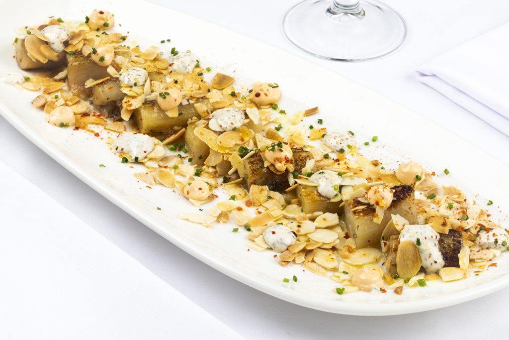 Puerro confitado a la plancha con un toque trufado y almendras tostadas